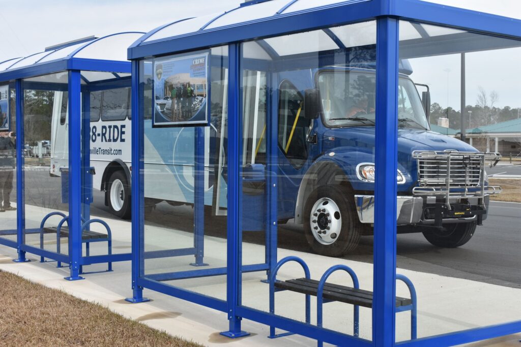 Back of blue bus shelter with passenger information displayed and seating for two