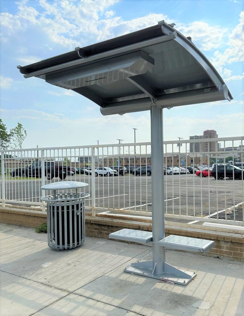 Bus shelter canopy with two seats and a trash receptacle