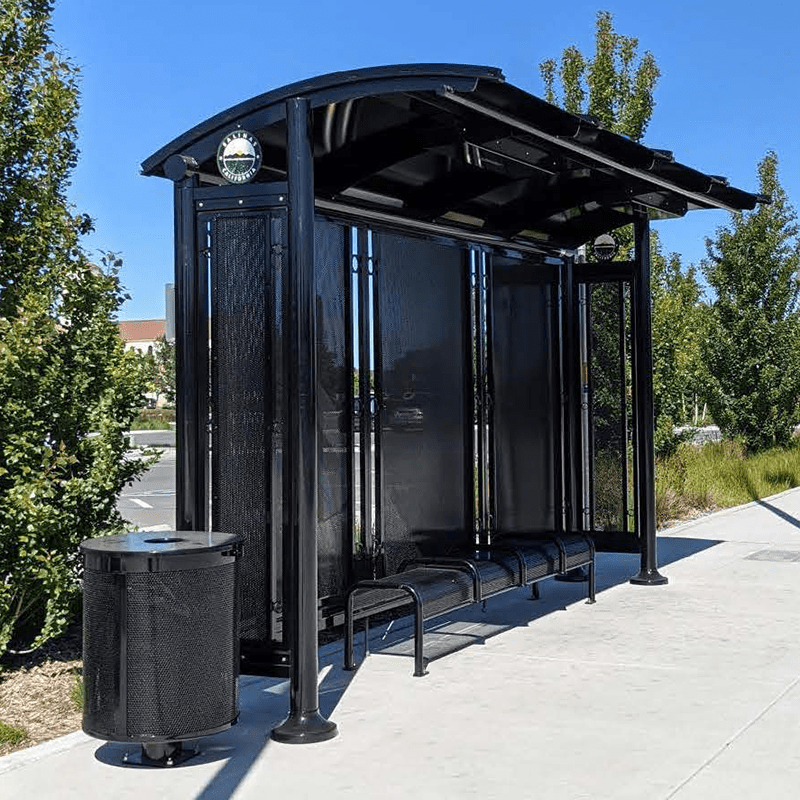 An all black custom signa sunset bus shelter includes a round trash receptable and bench seating