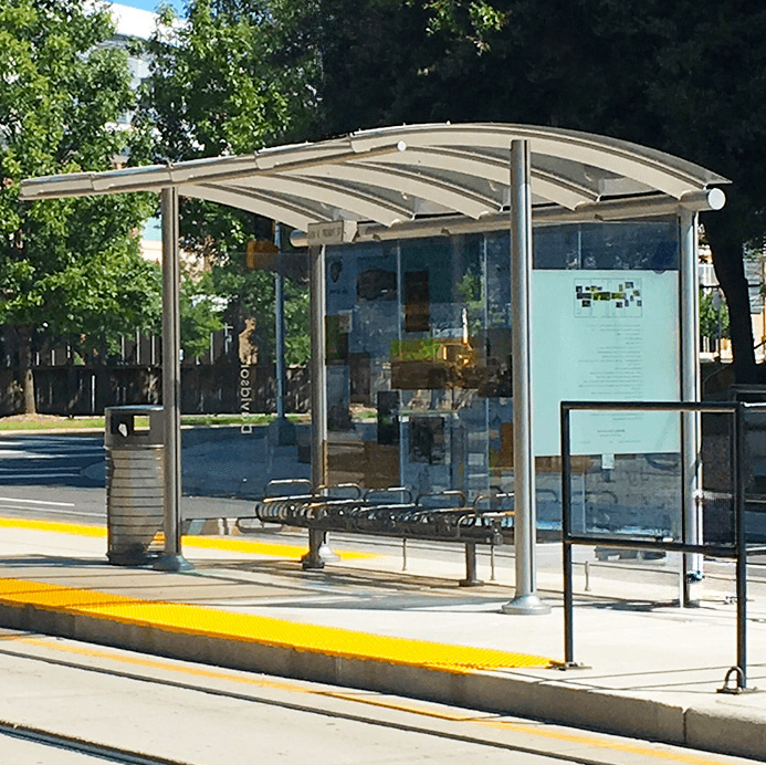 BRT bus shelter with rider information posted to the inside of the left side of the shelter with seating and trash receptacles