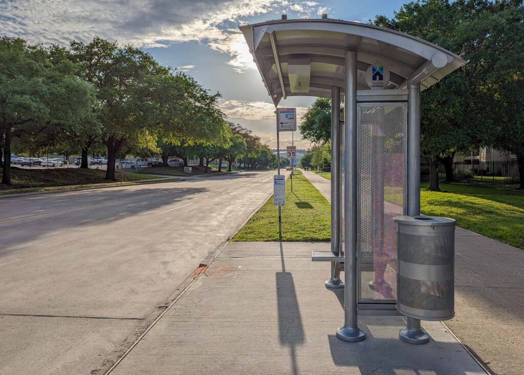 Right side profile of a bus shelter in Houston with a trash receptacle attached and bench seating for two