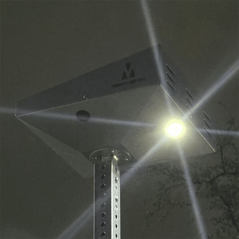 The top of a light post is seen at night.