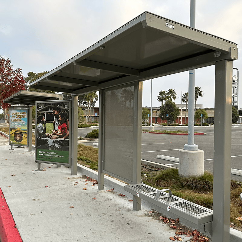 Left side view of a Siga Custom bus shelter with two advertising displays, bench seating and standing room