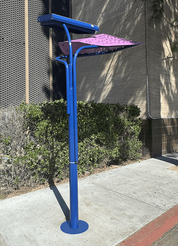 A signa custom bus shelter is seen from the left with a blue post and a purple leaf shaped top.