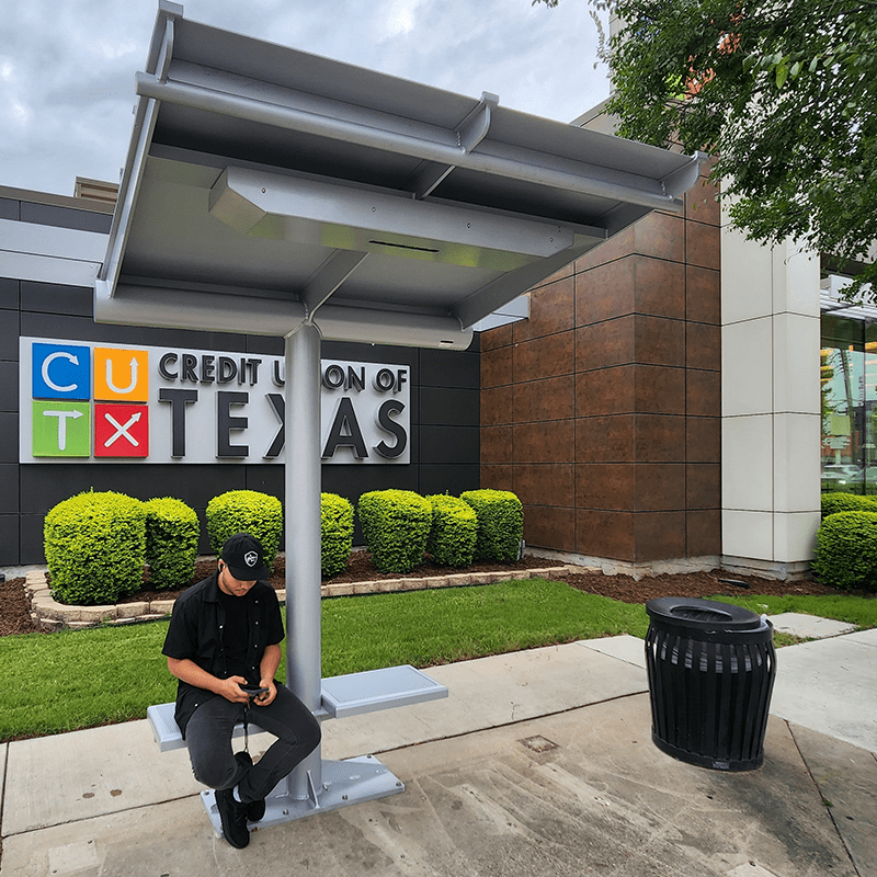 An Ecoshade is seen from the front with a rider seated on the left seat attached to the Ecoshade post.