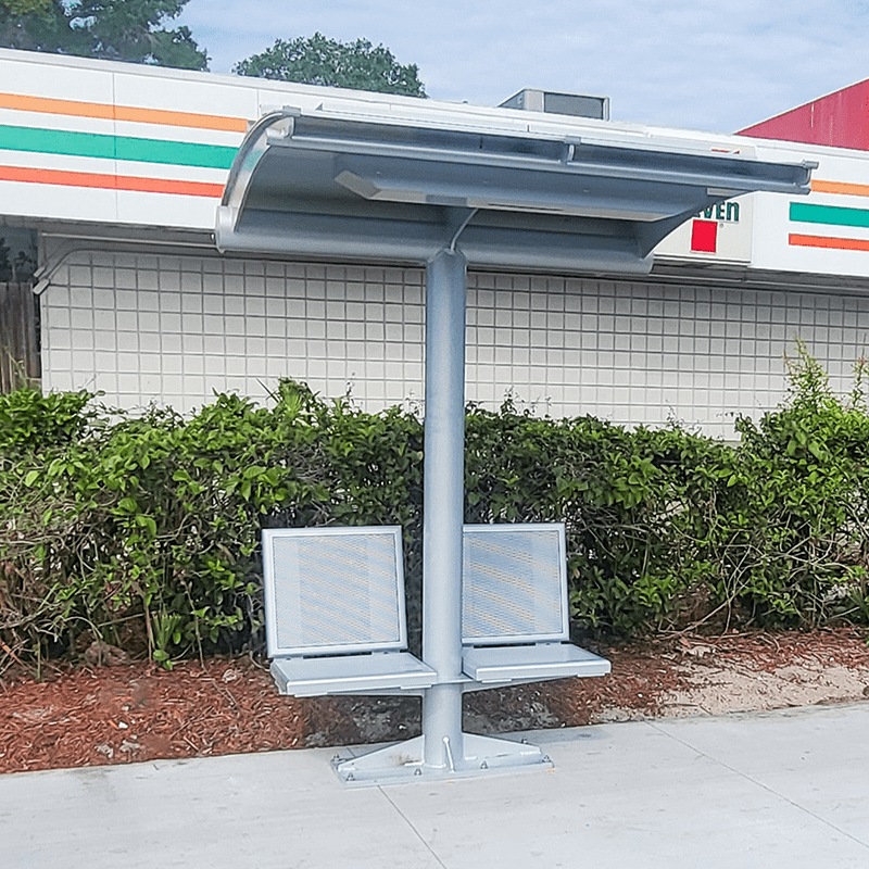 A signa sunset is seen outside a 7/11 convenience store with two seats attached to either side of the shelter post.