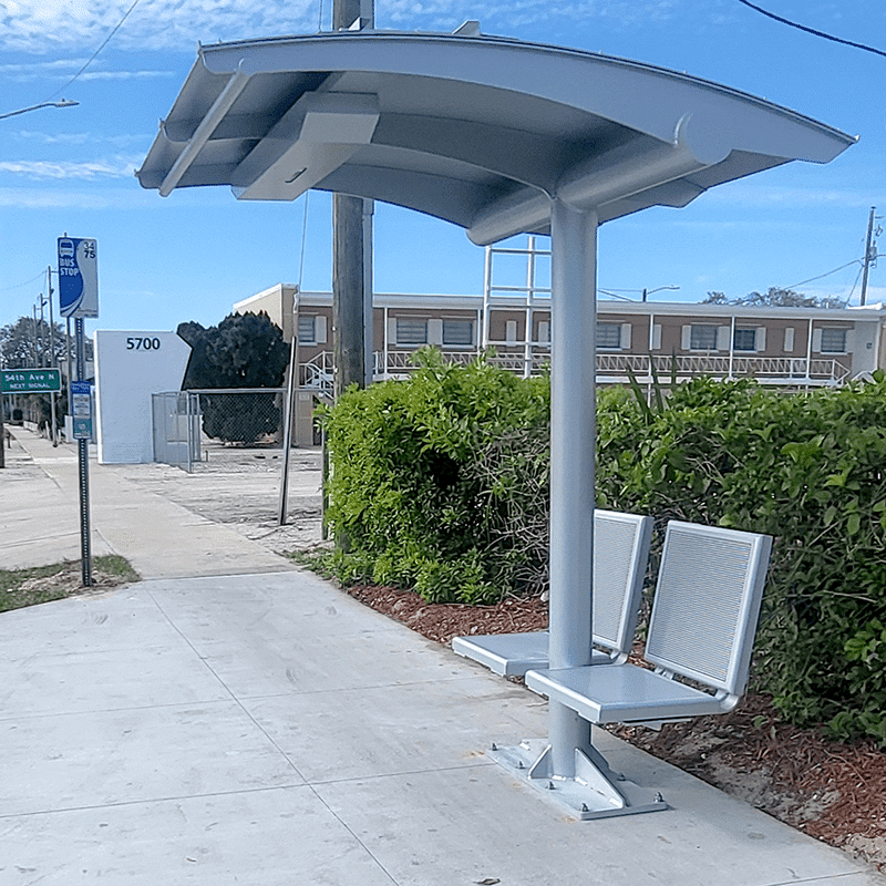 A signa sunset bus shelter is seen from the right side with two backed seats attached to either side of the shelter's post.