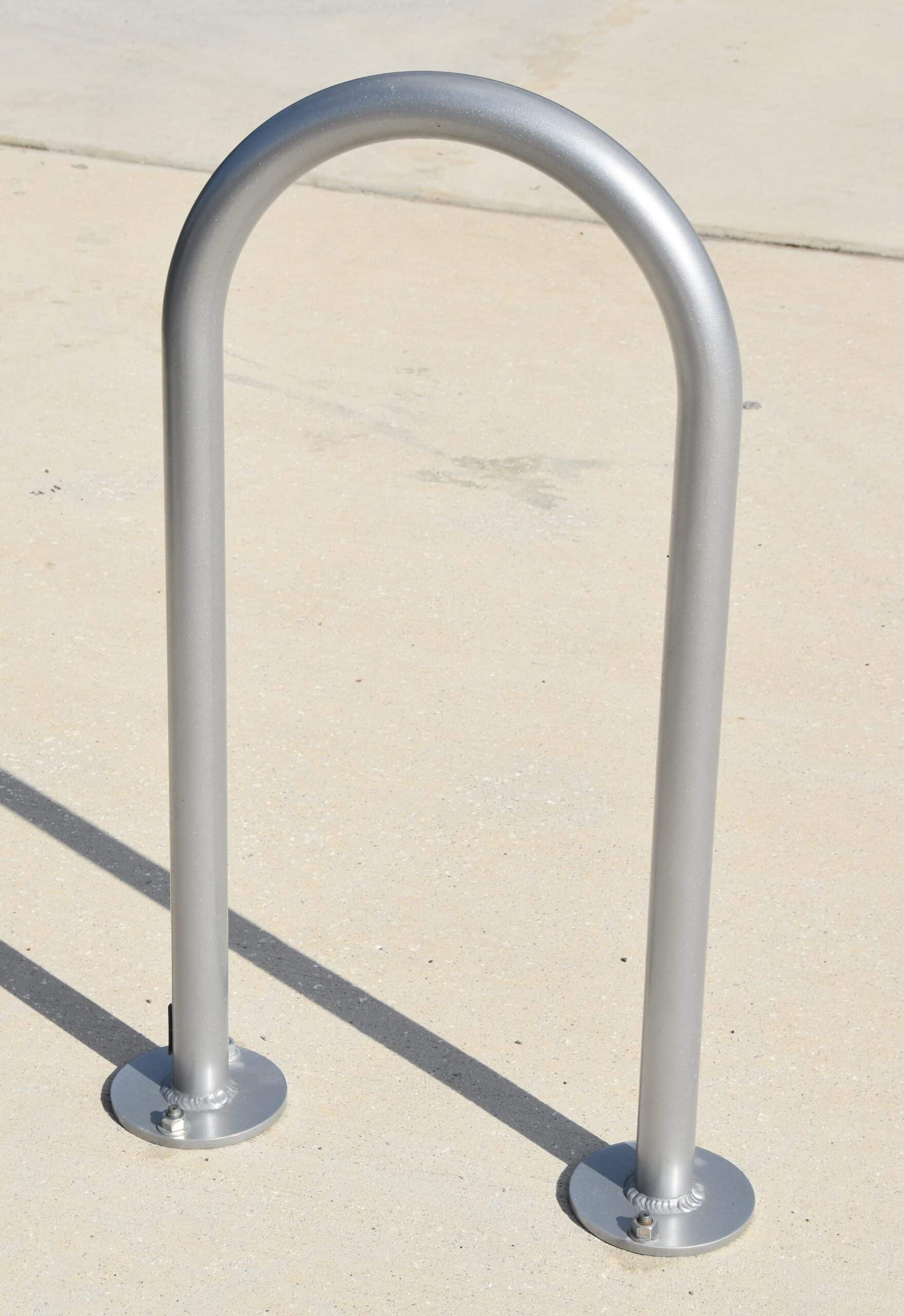 A silver metal bike stand is seen from the front with it nicely secured to the concrete.