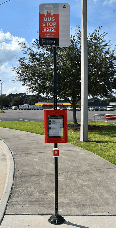 A bus stop 5212 is seen from the front with a post displaying bus stop information on top and rider information half way down the post.