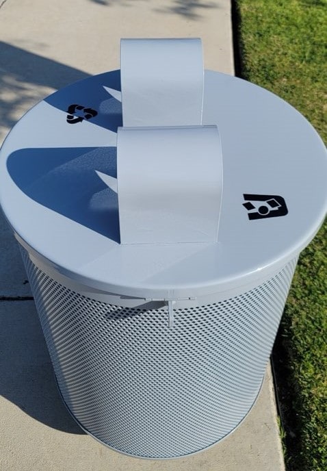 The top of a trash receptacle is seen with one logo on top for trash and one for recycling.