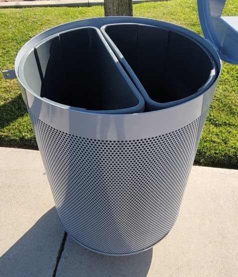 A trash receptacle is seen from the top with its lid off to show the two separate containers for trash and recycling.