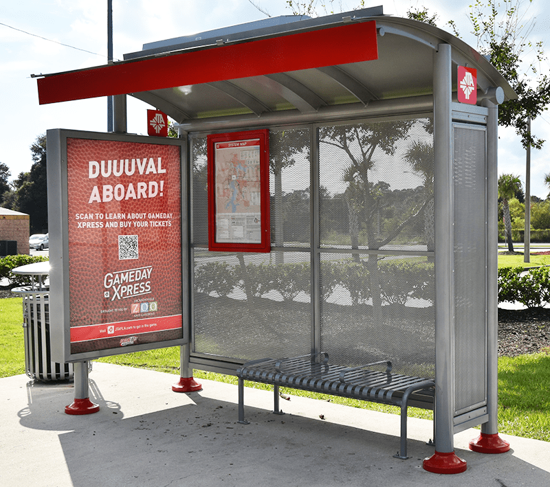 A siga sunset bus shelter is seen from the front right with a left side double sided advertising display, rider information on the back wall and a bench for three.