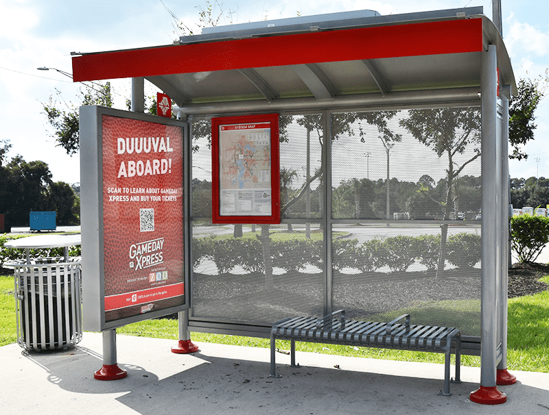 A siga sunset bus shelter is seen from the front with a left side double sided advertising display, a trash receptacle on the outside left, rider info on the inside left and a bench with seating for three on the right.
