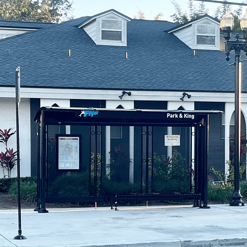 A signa sunset bus shelter is seen from the front with a rider display on the left and bench seating for four.
