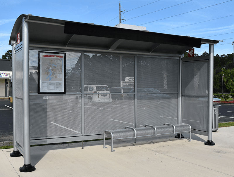 A signa sunset is seen from the front with a rider information display on the left inside of the shelter and bench seating for four.