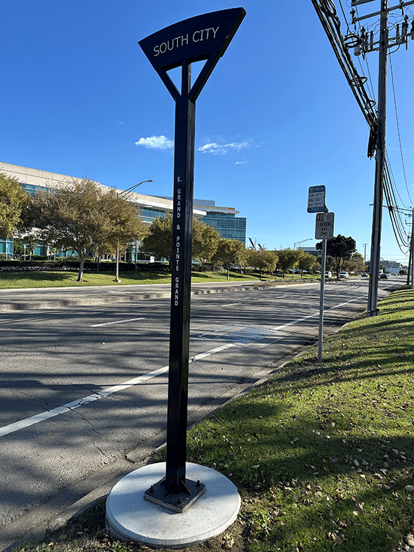 A bus stop post is seen in full length from the front with signage on top reading South City.