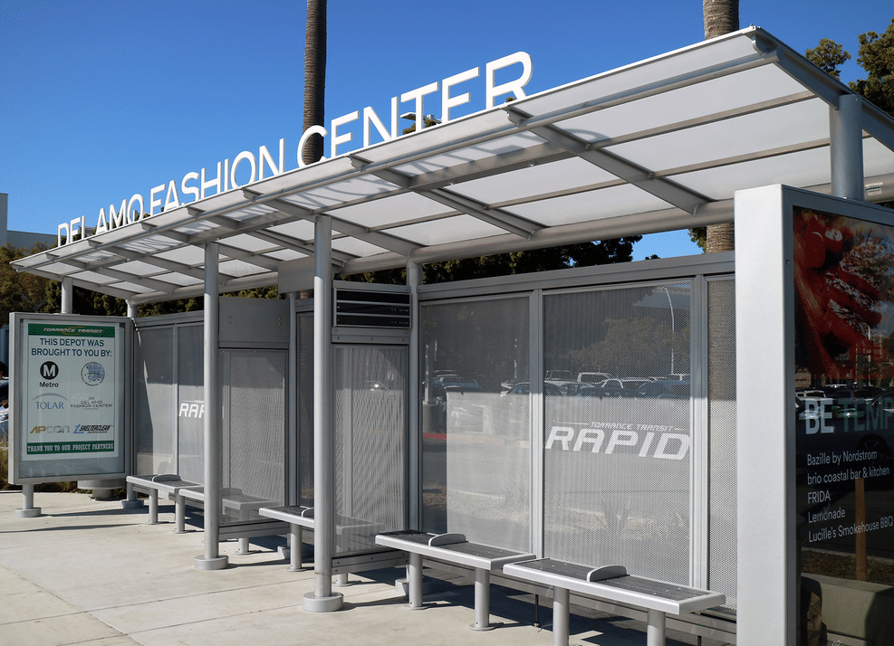 A bus shelter at Del Amo Fashion Center with ample seating and a double sided advertising display on the left side.